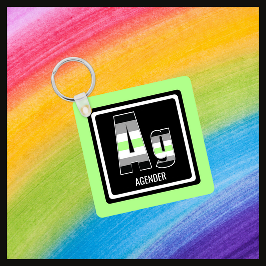 Keychain with the Element symbol (Ag) and name (Agender) with a design based on the colors of that element’s flag in a black square with a green background. Behind the keychain is a rainbow background.