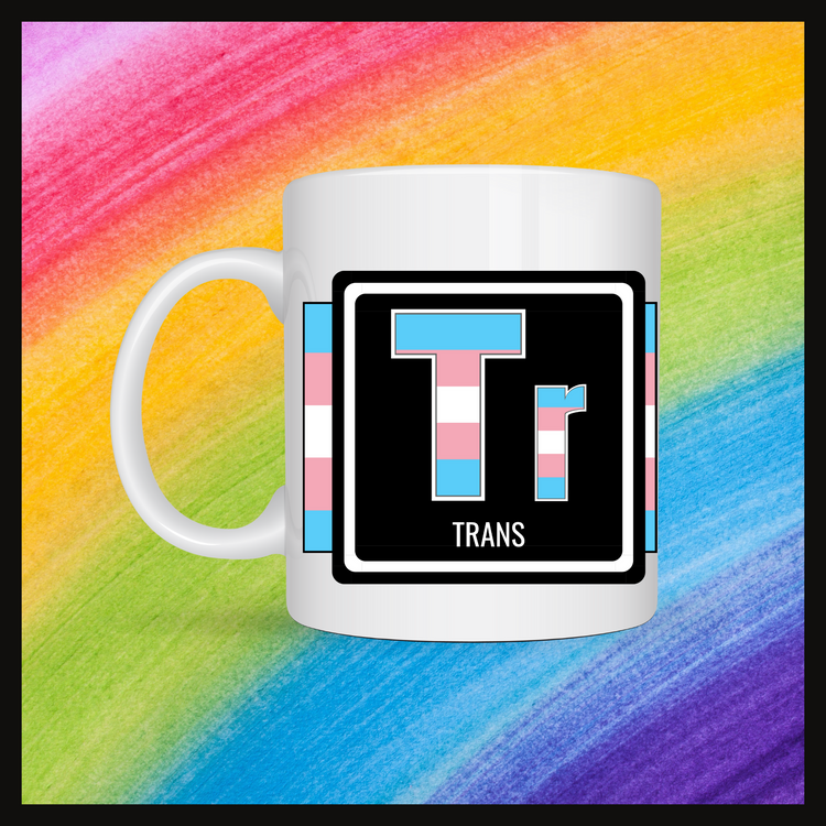 White mug with a 3 inch square containing the element’s symbol (Tr) and name (Trans). Symbol is made with the colors of that element’s flag in a black square with the element’s flag behind the square. Behind the mug is a rainbow background.