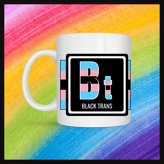 White mug with a 3 inch square containing the element’s symbol (Bt) and name (Black Trans). Symbol is made with the colors of that element’s flag on a black background. Behind the mug is a rainbow background.
