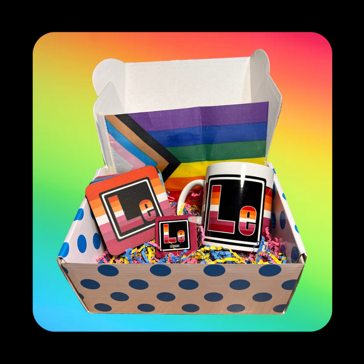 This is our Lesbian Element Gift Box - on a rainbow background inside a dotted blue box that holds a Queer Element Mug, Keychain and a set of our LGBTQ Coasters