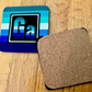 The Gay Element coaster. On the left is the front of the Gay element with the colors of the Gay flag. On the right is te back of our coasters, which have cork across the back of the coaster. 
