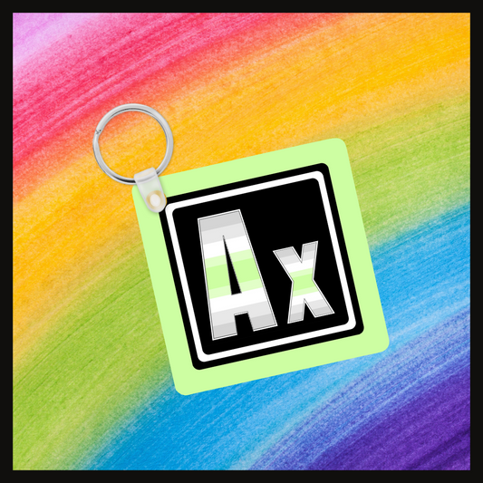 Keychain with the  Element symbol (Ax)  with a design based on the colors of that element’s flag in a black square with a green background. Behind the keychain is a rainbow background.