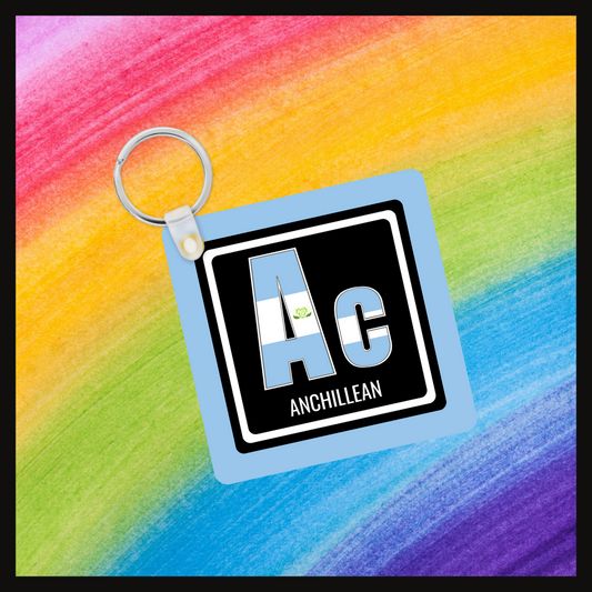 Keychain with the  element symbol (Ac) and name (Anchillean) with a design based on the colors of that element’s flag in a black square with a blue background. Behind the keychain is a rainbow background.