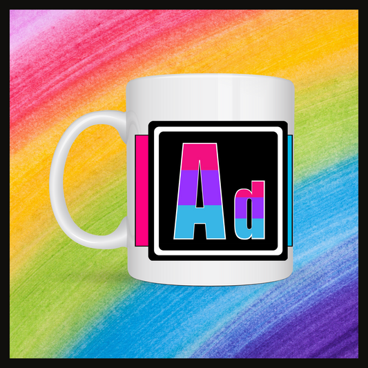 White mug with a 3 inch square containing the element’s symbol (Ad). Symbol is made with the colors of that element’s flag on a black background. Behind the keychain is a rainbow background.