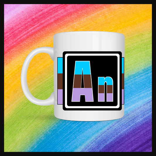 White mug with a 3 inch square containing the element’s symbol (An). Symbol is made with the colors of that element’s flag in a black square with the element’s flag behind the square. Behind the mug is a rainbow background.