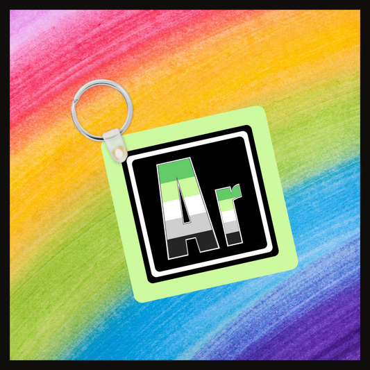 Keychain with the element symbol (Ar) with a design based on the colors of that element’s flag in a black square with a green background. Behind the keychain is a rainbow background.