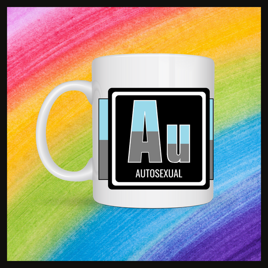 White mug with a 3 inch square containing the element’s symbol (Au) and name (Autosexual). Symbol is made with the colors of that element’s flag in a black square with the element’s flag behind the square. Behind the mug is a rainbow background.