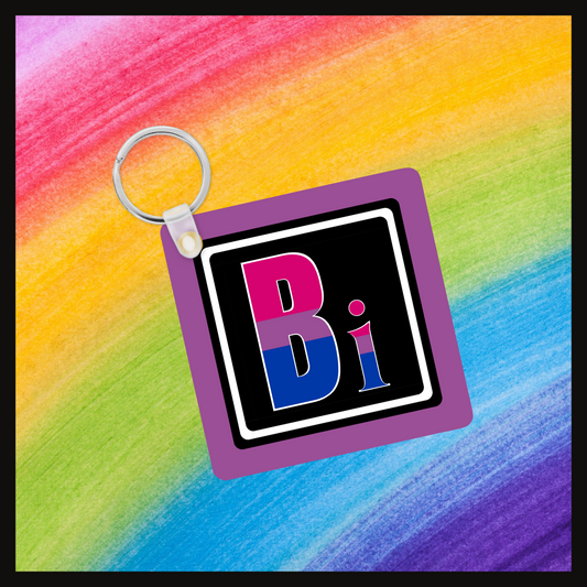 Keychain with the element symbol (Bi) with a design based on the colors of that element’s flag in a black square with a purple background. Behind the keychain is a rainbow background.