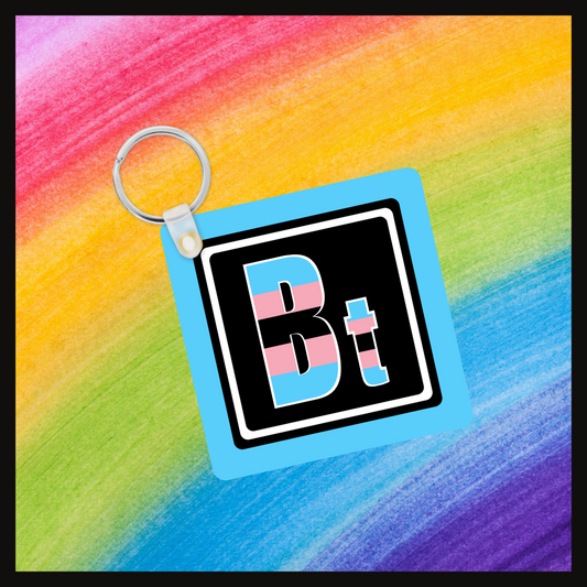 Keychain with the element symbol (Bt) with a design based on the colors of that element’s flag in a black square with a blue background. Behind the keychain is a rainbow background.