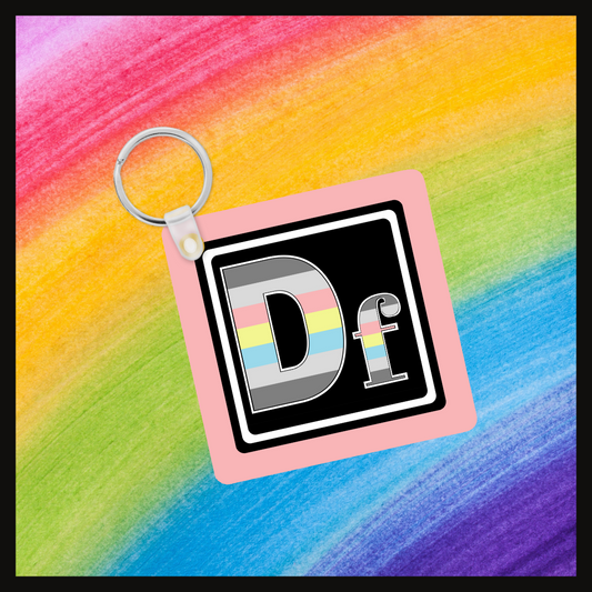 Keychain with the element symbol (Df) with a design based on the colors of that element’s flag in a black square with a pink background. Behind the keychain is a rainbow background.