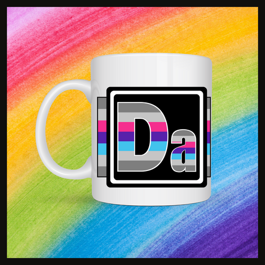 White mug with a 3 inch square containing the element’s symbol (Da). Symbol is made with the colors of that element’s flag in a black square with the element’s flag behind the square. Behind the mug is a rainbow background.