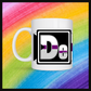 White mug with a 3 inch square containing the element’s symbol (De). Symbol is made with the colors of that element’s flag in a black square with the element’s flag behind the square. Behind the mug is a rainbow background.