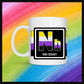 White mug with a 3 inch square containing the element’s symbol (Nb) and name (Non-binary). Symbol is made with the colors of that element’s flag in a black square with the element’s flag behind the square. Behind the mug is a rainbow background.